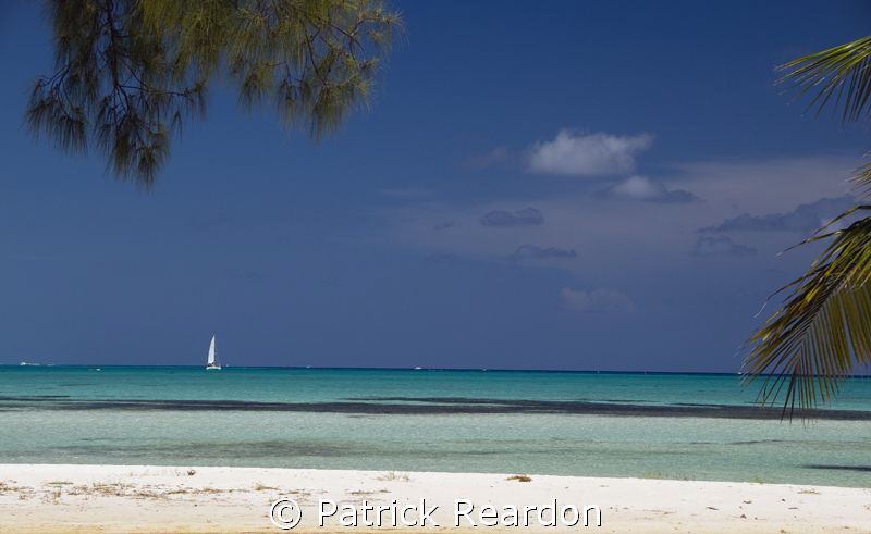 A sailboat passes by Cayman Kai, on the North shore of Gr... by Patrick Reardon 