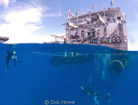 Split of diving boat with divers on ladder and approachin... by Dick Howe 