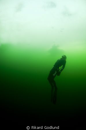 Freediver diving under the ice in Sweden by Rikard Godlund 
