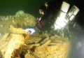 At 165 feet, a Nova Scotia tech diver examines a portion of the munitions cargo remaining on the Empire Kingfisher wrecked off Port LaTour. Nikonos V, 12mm Sea & Sea lens  dual Ikelite 150 strobes, Fuji 400 asa film. Cropped & colour corrected. 