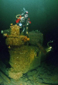 Divers explore a Sherman-Grant tank lying on its side from the wreck of the Kolkhosnik lost off Halifax in 1942. Depth 145 feet. Nikonos V, 12mm Sea & Sea lens and dual Ikelite 150's, manual exposure. Cropped and colour corrected. 