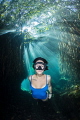 Freediver Natalia swimming through the sunlight broken up by the freshwater mangroves of Cenote Cristalino