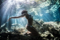 Freediver Model Natalia embracing the sunlight beaming through the waters surface of cenote Dos Ojos in Mexico