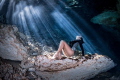 Freediver basking in the sun rays beaming through the surface of one of the many cenotes in the Riviera Maya, Mexico