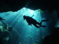 The sun shines on a diver, from the green jungle above, as he passes a sink hole in the Chac Mool cave system. Dome port used. Natural ligth, no filters.