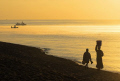 As the sunrises, life wakes up along the western shores of Lake Malawi at Senga Bay, with fishermen unloading their catches and woman carrying water on her head and child walking alongside