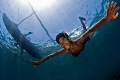 A young boy free diving from his dug out canoe with home made wooden googles..